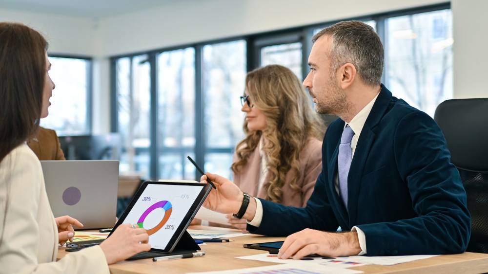 Gerentes de una pyme analizando en su portátil una tabla comparativa para elegir el mejor CRM en España, evaluando HubSpot, Zoho y Pipedrive.