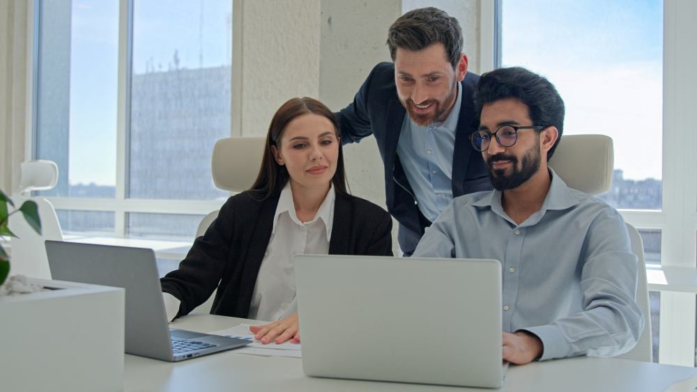 Primer plano de tres personas revisando datos en un portátil.