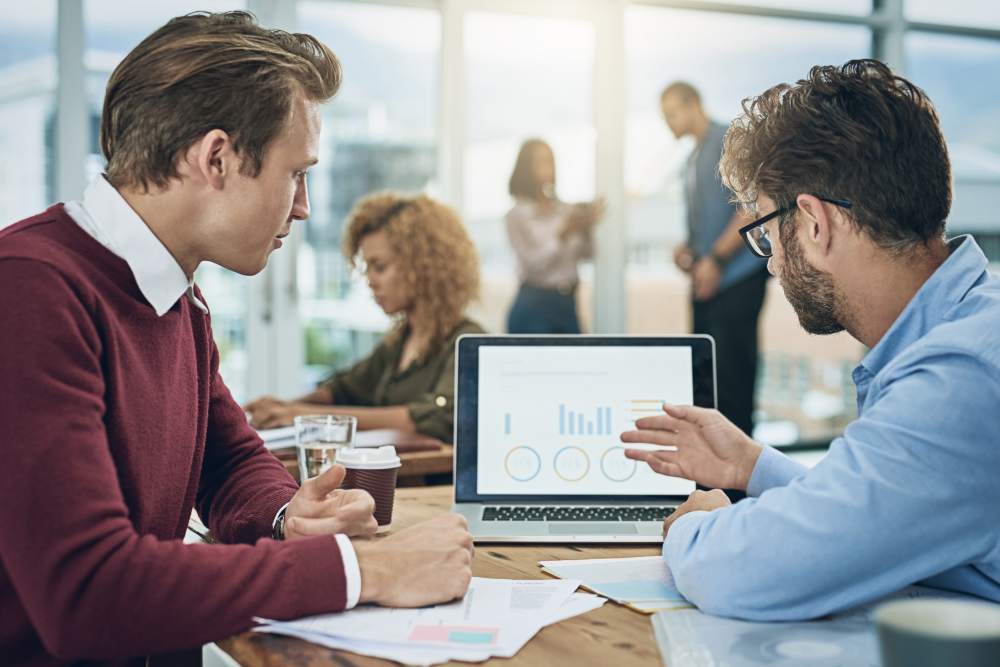 Dos profesionales B2B analizando gráficas de ventas en equipo para decidir cómo empezar con HubSpot CRM gratis y cuándo escalar.