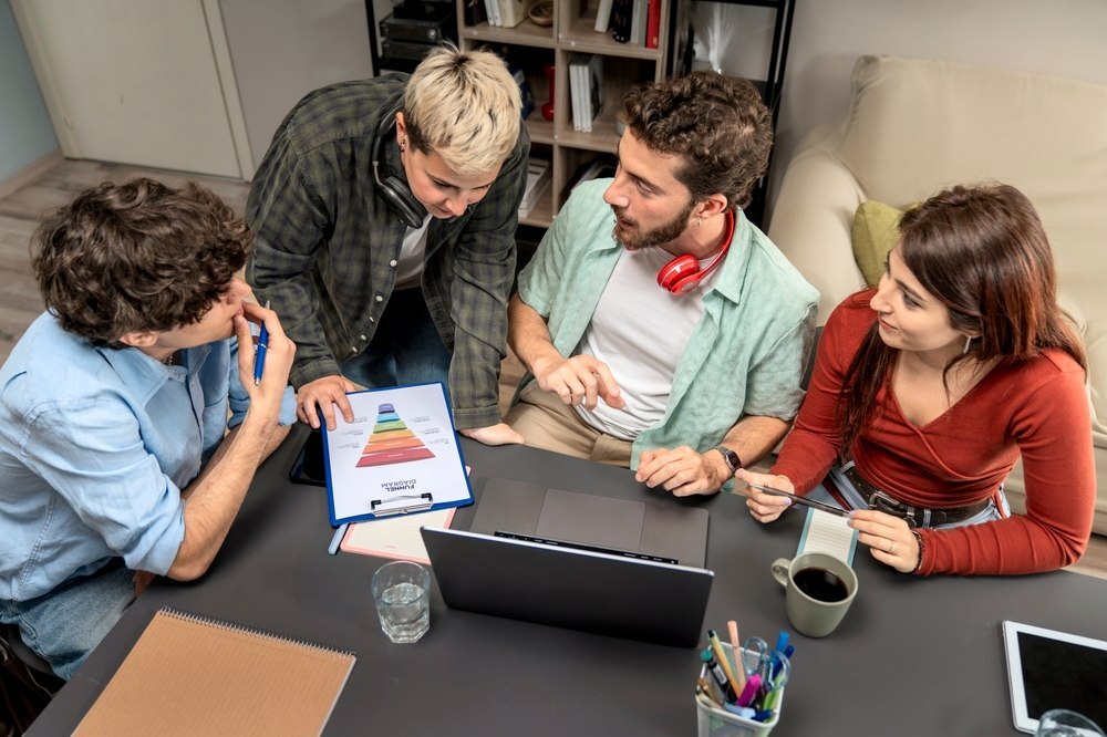 Grupo de estudiantes y profesionales trabajando en estrategias de contenidos educativos con laptop y material gráfico.