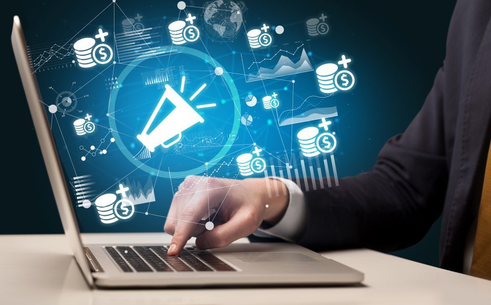 Mano usando un portátil con gráficos y un ícono de megáfono que representan servicios de IA